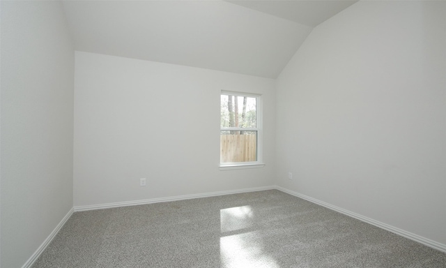 carpeted spare room with vaulted ceiling