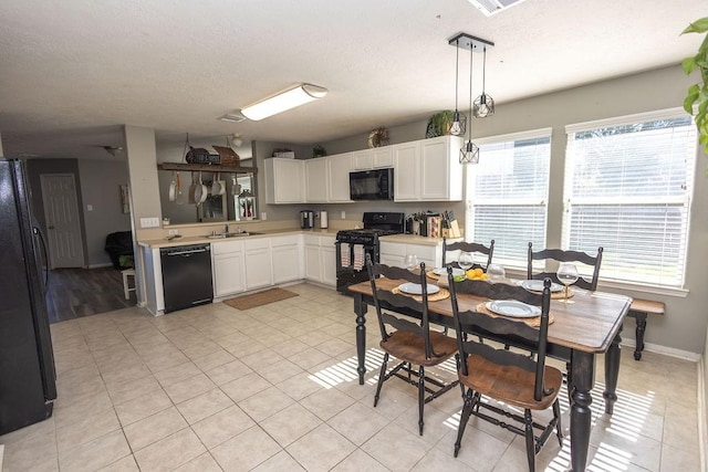 kitchen featuring black appliances, white cabinets, sink, hanging light fixtures, and light tile patterned floors