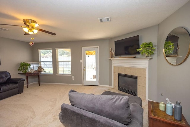 living room featuring light colored carpet, ceiling fan, and a tiled fireplace