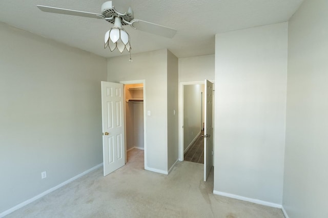 unfurnished bedroom with ceiling fan, light colored carpet, a walk in closet, and a closet