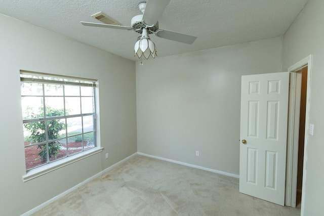 carpeted spare room with a textured ceiling and ceiling fan