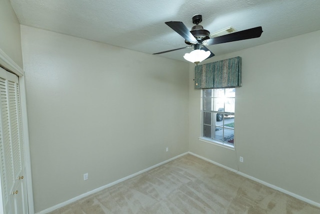 carpeted empty room featuring a textured ceiling and ceiling fan