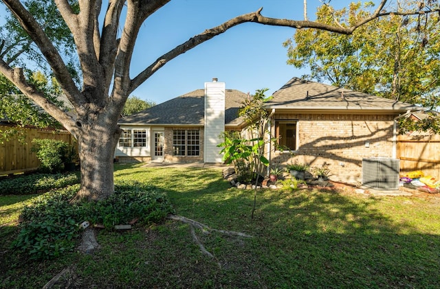 back of property featuring central air condition unit and a lawn