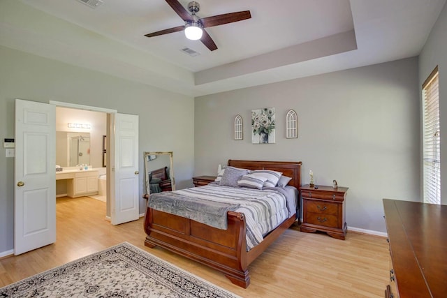 bedroom with a raised ceiling, ceiling fan, and light hardwood / wood-style floors