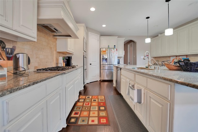 kitchen with dark hardwood / wood-style floors, light stone countertops, custom range hood, and appliances with stainless steel finishes