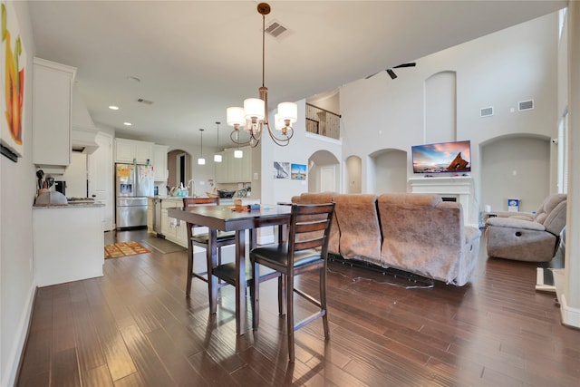 dining room featuring a notable chandelier, a towering ceiling, and dark wood-type flooring