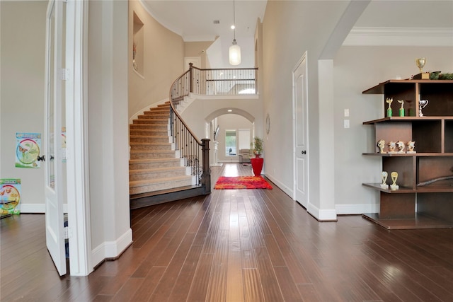 entrance foyer featuring ornamental molding, dark wood-type flooring, and a high ceiling