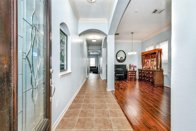 entryway featuring tile patterned floors, ornamental molding, and a notable chandelier