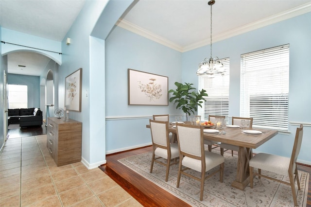 tiled dining space with a chandelier, plenty of natural light, and crown molding