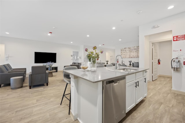 kitchen with sink, stainless steel dishwasher, an island with sink, light hardwood / wood-style floors, and white cabinetry