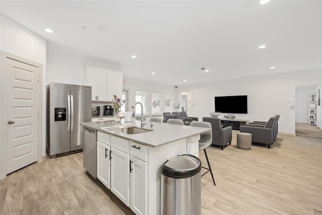 kitchen featuring a kitchen island with sink, sink, light hardwood / wood-style flooring, white cabinetry, and stainless steel appliances