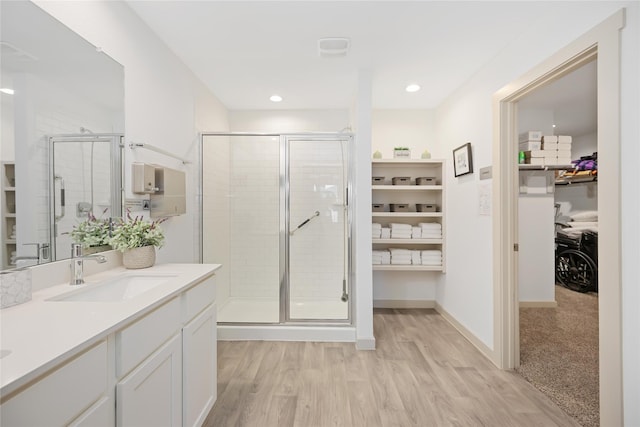 bathroom with wood-type flooring, vanity, and a shower with door