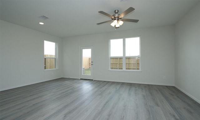 spare room with ceiling fan, light hardwood / wood-style floors, and a wealth of natural light