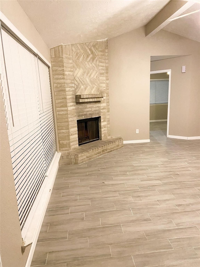 unfurnished living room featuring vaulted ceiling with beams and a fireplace