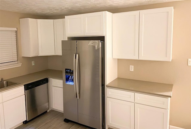 kitchen with stainless steel appliances, light hardwood / wood-style floors, a textured ceiling, and white cabinets