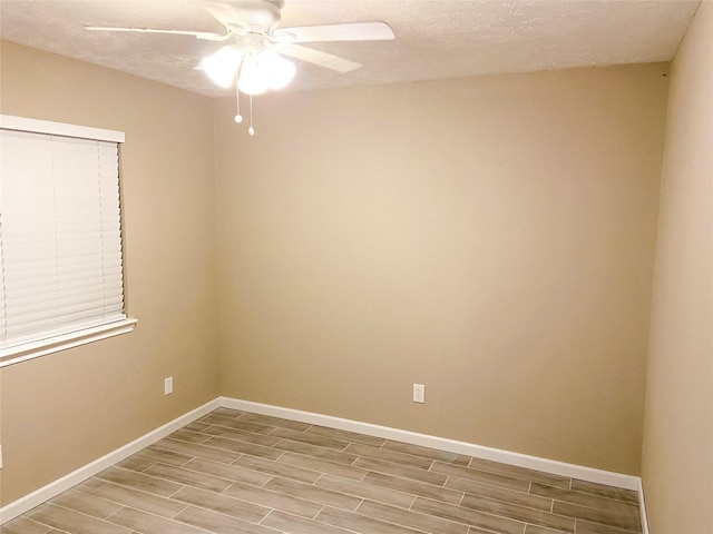 unfurnished room with ceiling fan and a textured ceiling