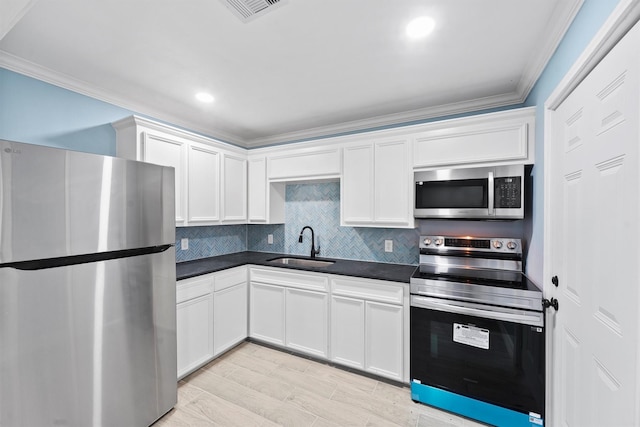 kitchen featuring white cabinets, sink, decorative backsplash, ornamental molding, and stainless steel appliances