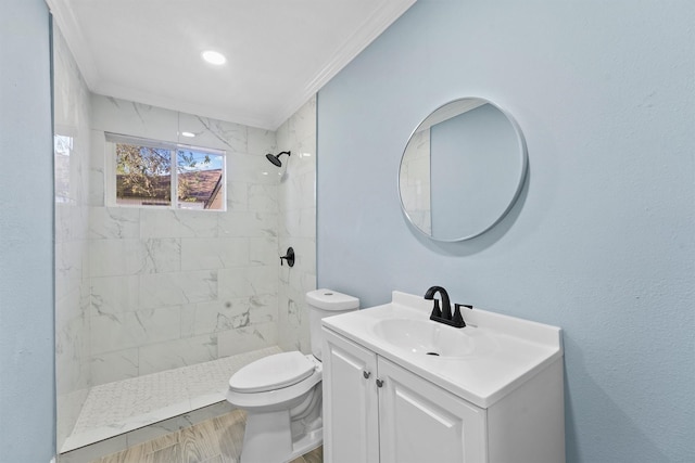 bathroom with tiled shower, toilet, vanity, and ornamental molding