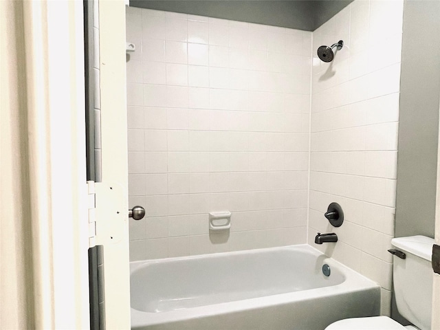 bathroom featuring toilet and tiled shower / bath