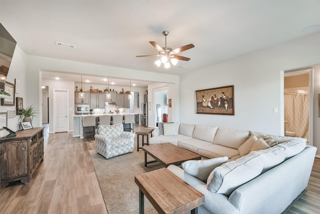 living room with light hardwood / wood-style flooring and ceiling fan