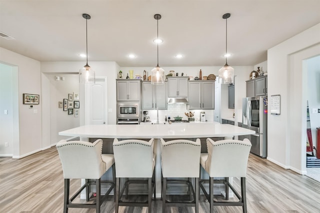 kitchen with gray cabinets, a large island, hanging light fixtures, and stainless steel appliances