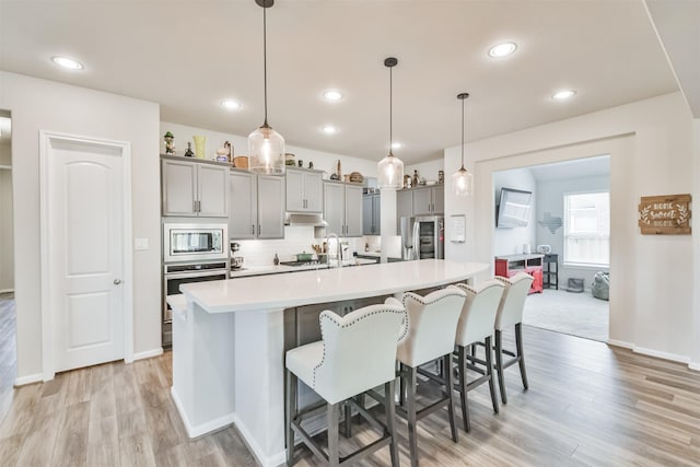 kitchen with gray cabinetry, a large island, hanging light fixtures, and appliances with stainless steel finishes