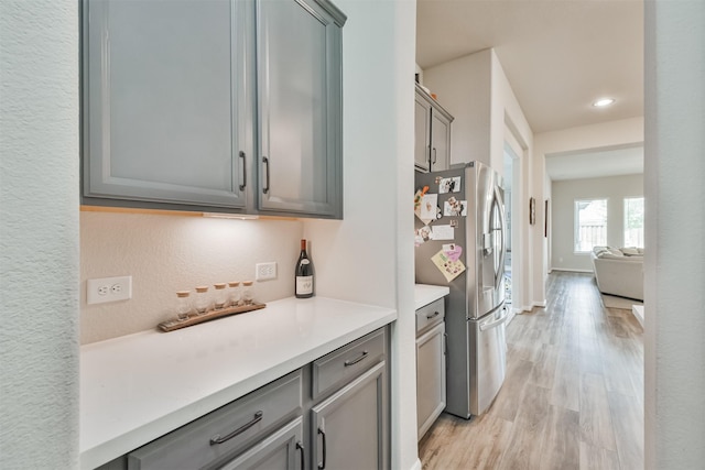 kitchen with stainless steel fridge, light wood-type flooring, and gray cabinetry