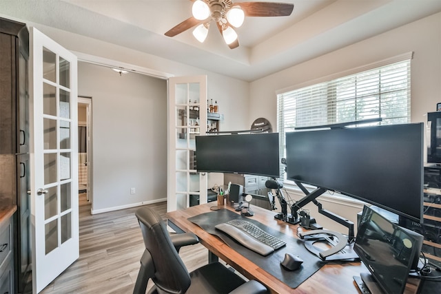 office with a tray ceiling, ceiling fan, french doors, and light hardwood / wood-style floors