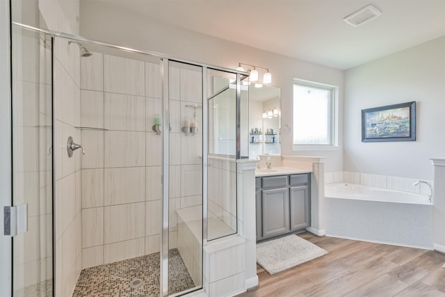 bathroom featuring hardwood / wood-style floors, vanity, and shower with separate bathtub