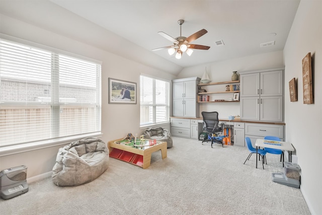 carpeted office space featuring built in desk, vaulted ceiling, and ceiling fan