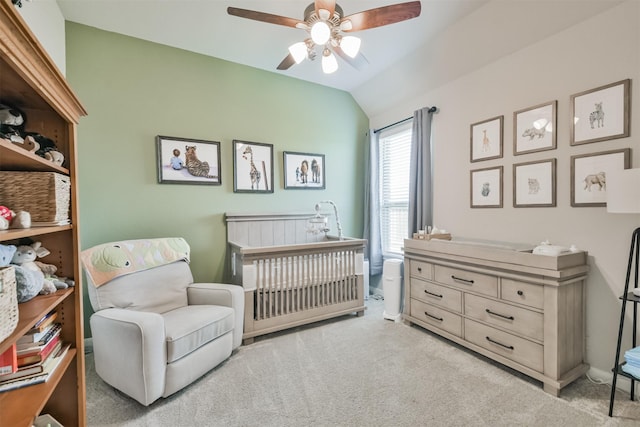 carpeted bedroom with a nursery area, lofted ceiling, and ceiling fan