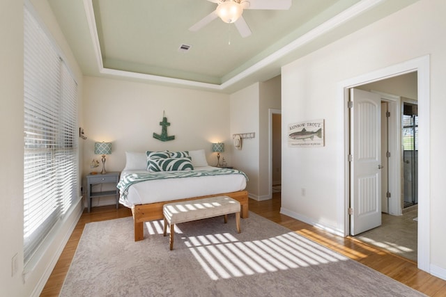 bedroom with hardwood / wood-style flooring, ceiling fan, and a tray ceiling