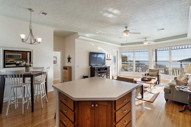 kitchen featuring a center island, ceiling fan with notable chandelier, hanging light fixtures, light wood-type flooring, and appliances with stainless steel finishes