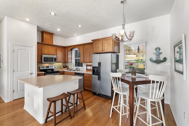 kitchen with sink, a center island, a notable chandelier, a breakfast bar area, and appliances with stainless steel finishes