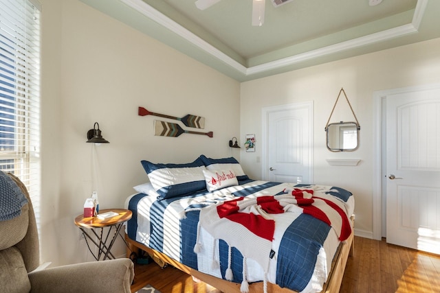 bedroom featuring wood-type flooring, a raised ceiling, and ceiling fan