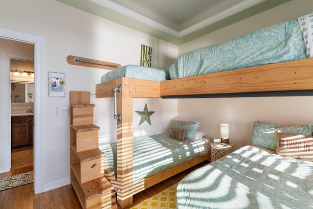 bedroom with ensuite bathroom, hardwood / wood-style floors, and crown molding