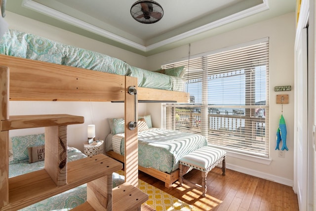 bedroom featuring a tray ceiling, crown molding, and hardwood / wood-style floors