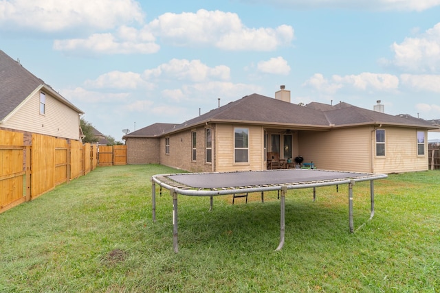 back of house with a yard and a trampoline