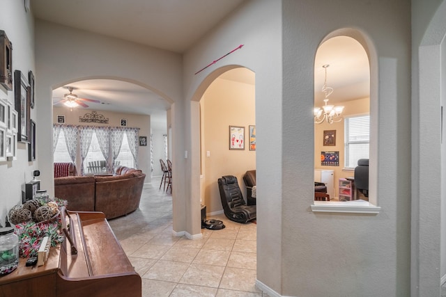 hall with light tile patterned floors and an inviting chandelier