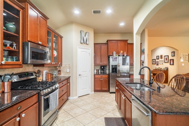 kitchen with tasteful backsplash, sink, dark stone counters, and stainless steel appliances