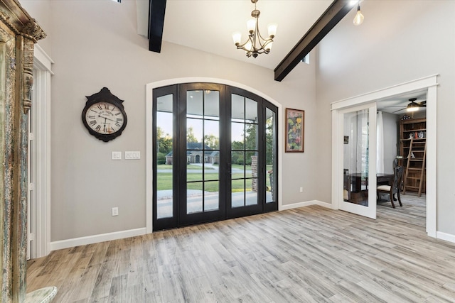 entryway with beamed ceiling, ceiling fan with notable chandelier, light wood-type flooring, and french doors