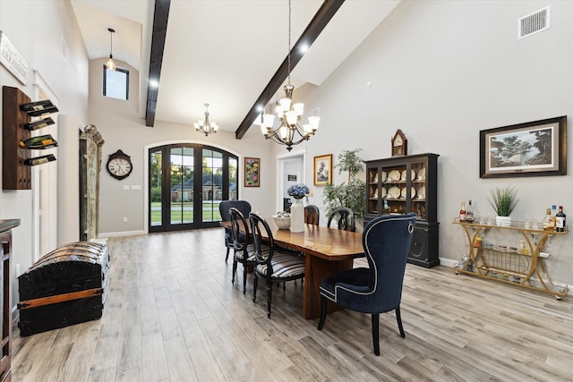 dining room featuring a chandelier, french doors, light wood-type flooring, and a towering ceiling