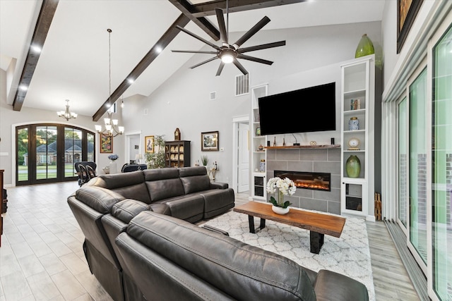 living room with ceiling fan with notable chandelier, beam ceiling, light hardwood / wood-style flooring, high vaulted ceiling, and a tiled fireplace