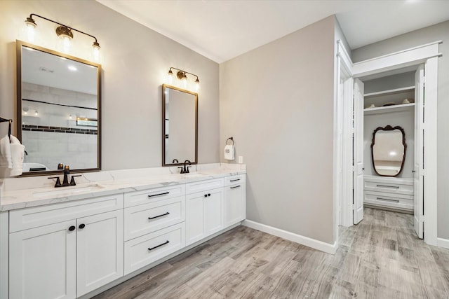 bathroom featuring vanity, a tile shower, and wood-type flooring