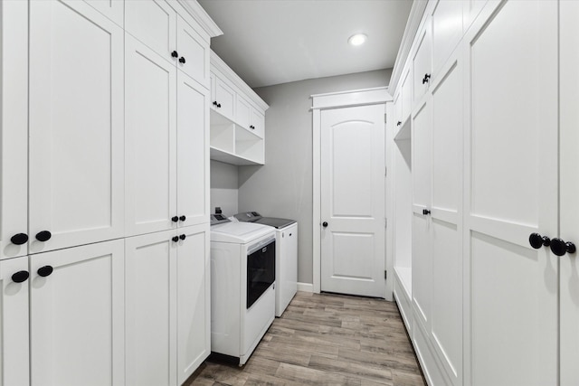 laundry area with cabinets, light wood-type flooring, and washer and clothes dryer