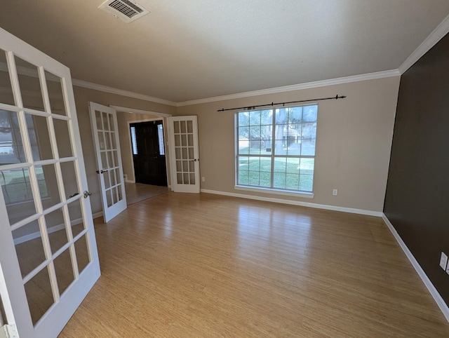 empty room featuring light hardwood / wood-style floors, ornamental molding, and french doors