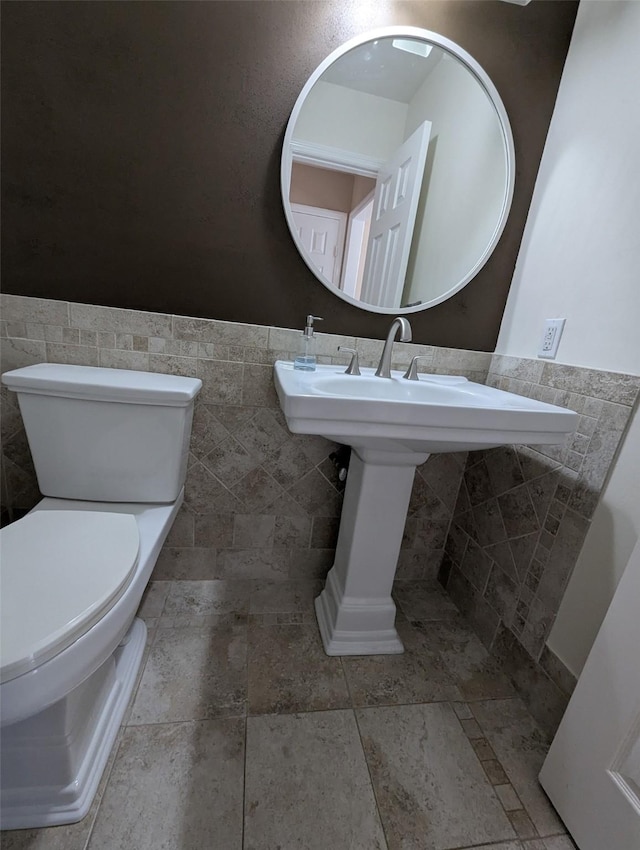 bathroom with tile walls and toilet