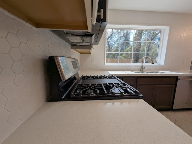 kitchen featuring decorative backsplash, light tile patterned flooring, sink, dark brown cabinetry, and appliances with stainless steel finishes