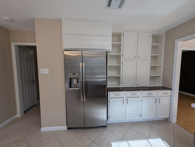 kitchen with stainless steel fridge with ice dispenser, white cabinetry, and light tile patterned flooring