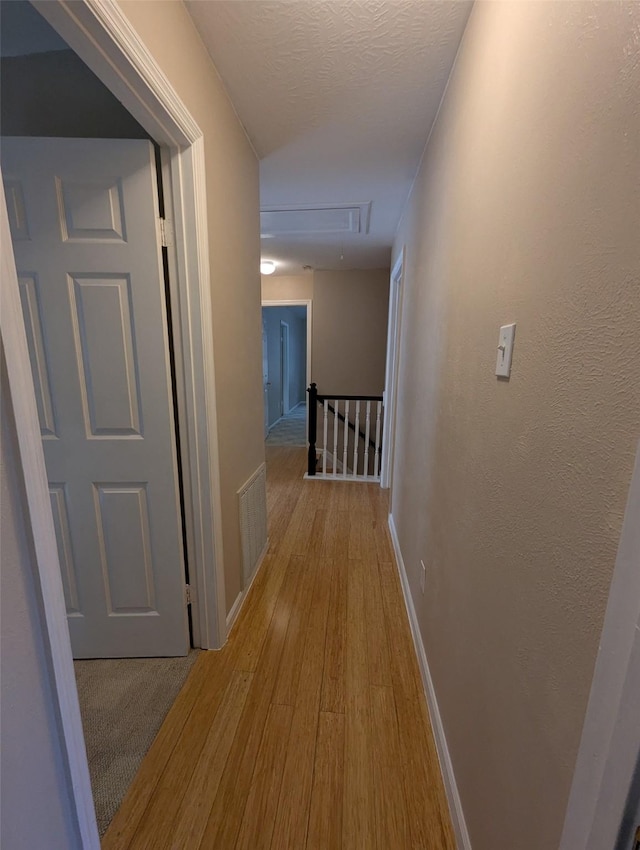 corridor featuring light hardwood / wood-style floors and a textured ceiling